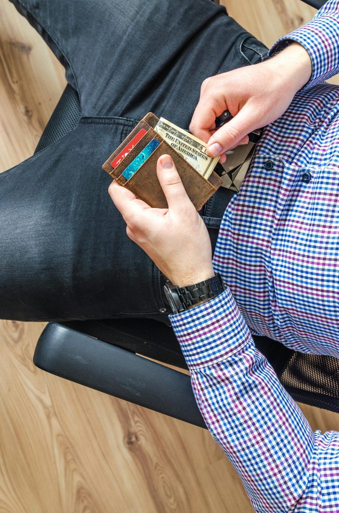 pexels-photo-928202-928202 Close-up of a man in casual attire holding a wallet and checking his credit cards indoors.